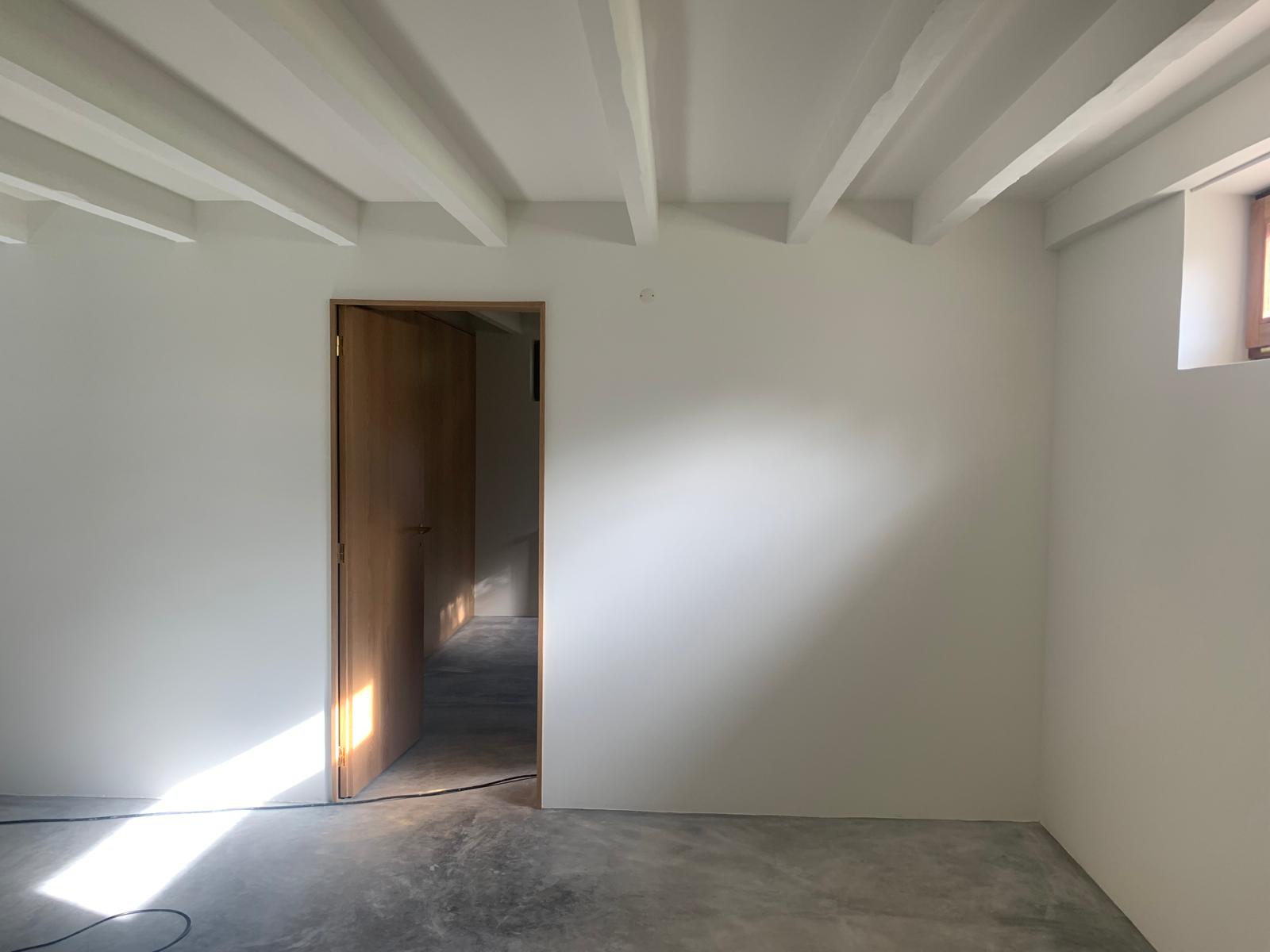 Room with painted timber beams, oak door and polished concrete floor