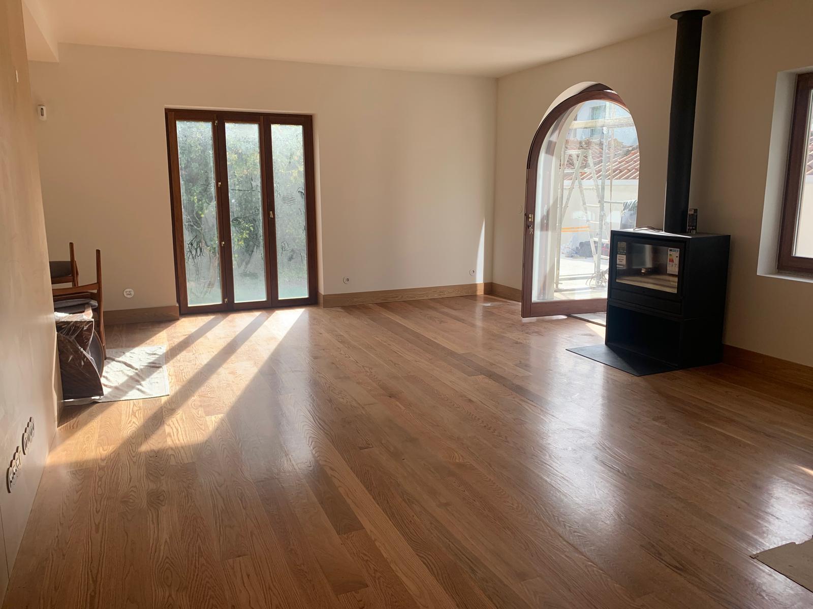 Sunlit living room with restored oak floor, arched glazed door and wood-burning stove